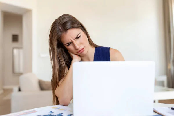 Bitkin hissediyorum. Hüsrana uğramış genç bir kadın yorgun görünüyor ve iş yerinde otururken boynuna masaj yapıyor.