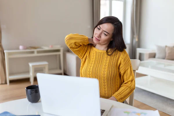 Bitkin hissediyorum. Hüsrana uğramış Asyalı kadın yorgun görünüyor ve iş yerinde otururken boynuna masaj yapıyor.