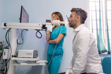 Adam klinikte spirometre kullanarak pulmoner fonksiyon testi ve spirometri yapıyor. Akciğerlerin Spirometrisi