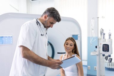 Kadın hasta, modern hastanedeki muayene prosedüründen sonra tomografiyle ilgili sorular soruyor.