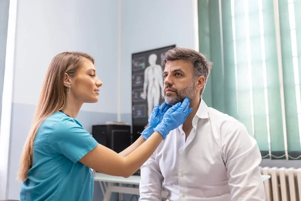 Terapist sisteminde profesyonel danışmanlık kavramı. Tıp bürosunda erkek bademciklerini muayene eden doktor kadının yakın portresi.
