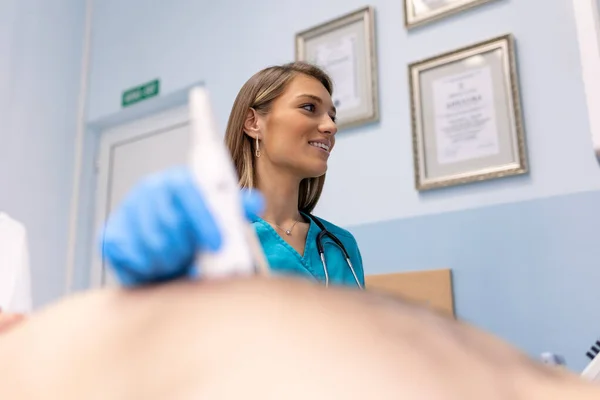 Kadın doktor, modern ultrason cihazları kullanıyor ve hastanede teşhis sırasında erkek hastanın kalbini muayene ediyor.