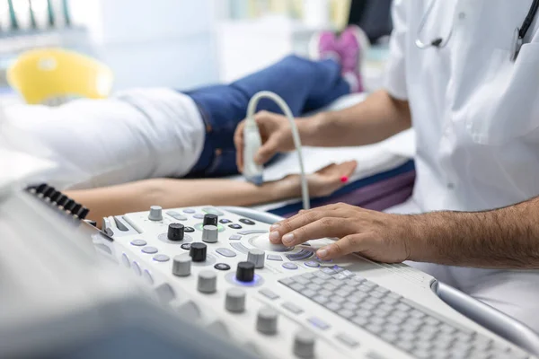 Kadın için ultrason terapisi yaparken erkek doktorun elinde özel bir aletle görüntüsü kesilmiş. Üst xtremities konseptinin damarlarının ultrasonu