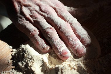 Yaşlı bir kadın hamur yoğuruyor.