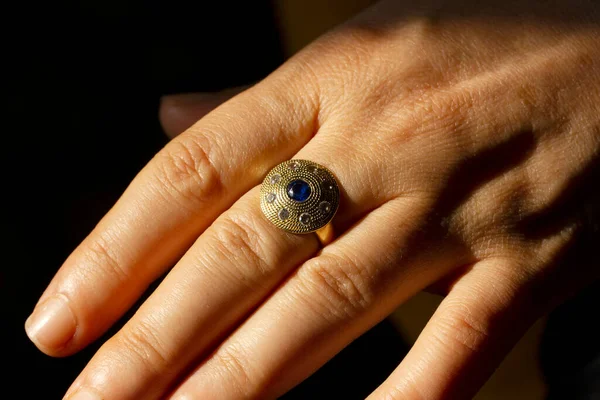 Gold ring with blue stone on finger