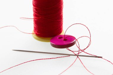 İki delikli düğme. İnce kırmızı iplik.