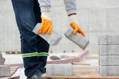 Paving taş işçisi şehir caddesinin inşaatı sırasında kaldırımları indiriyor..