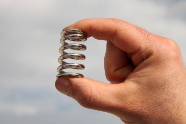 Mühendisin elinde metal yay var. Yeni üretilmiş metal yayları.