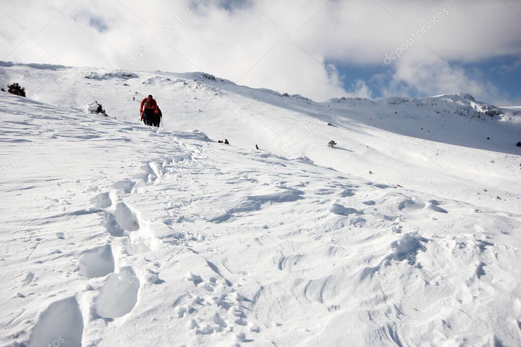 Group of mountaineers walking trough the mountains covered with snow