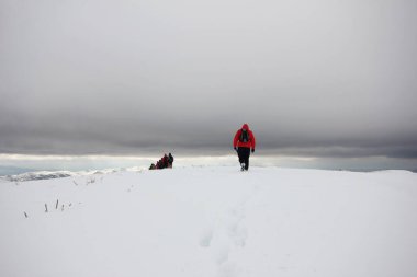 Dağlarda karla kaplı bir grup dağcı yürüyor.
