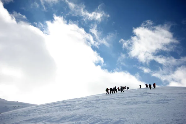 一队登山者走过被雪覆盖的群山 — 图库照片
