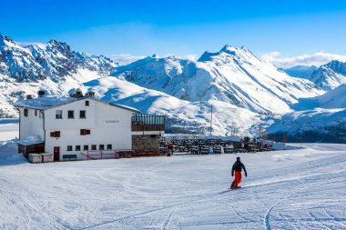 Livigno, İtalya - 3 Ocak 2018: Kayakçılar ve snowboardcular arka planda kış manzarası ile Alplerde geziyorlar