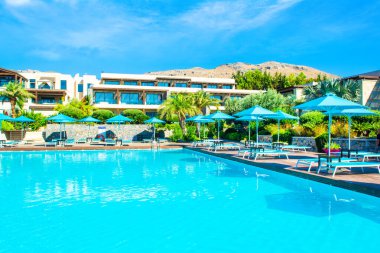 Rodos, Yunanistan - 18 Temmuz 2019: Rodos adasında güneşlik ve şemsiyeli lüks bir otelde açık havuz alanı