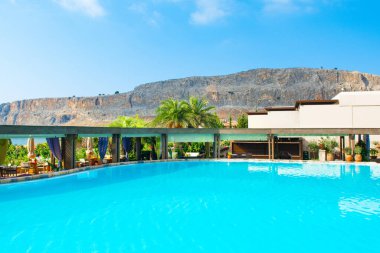 Rodos, Yunanistan - 18 Temmuz 2019: Rodos adasında güneşlik ve şemsiyeli lüks bir otelde açık havuz alanı