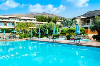 Rodos, Yunanistan - 18 Temmuz 2019: Rodos adasında güneşlik ve şemsiyeli lüks bir otelde açık havuz alanı