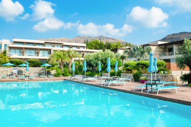 Rodos, Yunanistan - 18 Temmuz 2019: Rodos adasında güneşlik ve şemsiyeli lüks bir otelde açık havuz alanı