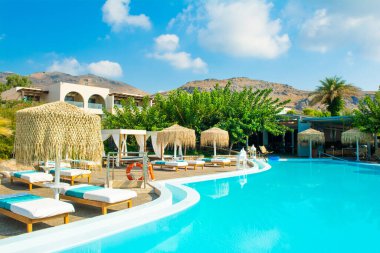 Rodos, Yunanistan - 18 Temmuz 2019: Rodos adasında güneşlik ve şemsiyeli lüks bir otelde açık havuz alanı
