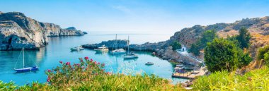 Rhodes Adası 'ndaki güzel St. Paul Körfezi' nin gün batımı manzarası. Dağ, kayalık plaj ve yat marinası.
