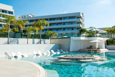 Limasol, Kıbrıs - 19 Mayıs 2021: Lüks otel Parklane 'deki havuz alanı Palmiye ağaçları ve tropikal bitkilerin gölgesinde güneşli güneşli bir tatil beldesi