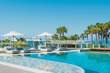Limasol, Kıbrıs - 19 Mayıs 2021: Lüks otel Parklane 'deki havuz alanı Palmiye ağaçları ve tropikal bitkilerin gölgesinde güneşli güneşli bir tatil beldesi