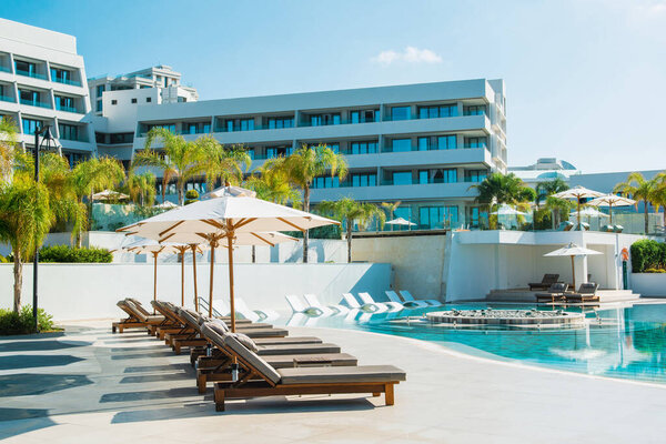 Лимассол, Кипр - 19 мая 2021 года: Площадь бассейна в роскошном отеле с шезлонгами в тени пальм и тропических растений