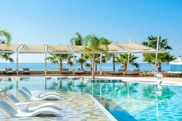 Limasol, Kıbrıs - 19 Mayıs 2021: Lüks otel Parklane 'deki havuz alanı Palmiye ağaçları ve tropikal bitkilerin gölgesinde güneşli güneşli bir tatil beldesi