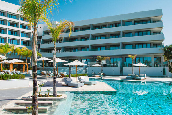 Лимассол, Кипр - 19 мая 2021 года: бассейн в роскошном современном отеле с шезлонгами в тени пальм и тропических растений