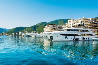 Tivat, Karadağ - 28 Haziran 2021: Porto Karadağ 'daki yat marinasının deniz kenarındaki konutları ve güzel gezinti alanlarıyla gün batımı manzarası