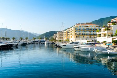 Tivat, Karadağ - 28 Haziran 2021: Porto Karadağ 'daki yat marinasının deniz kenarındaki konutları ve güzel gezinti alanlarıyla gün batımı manzarası