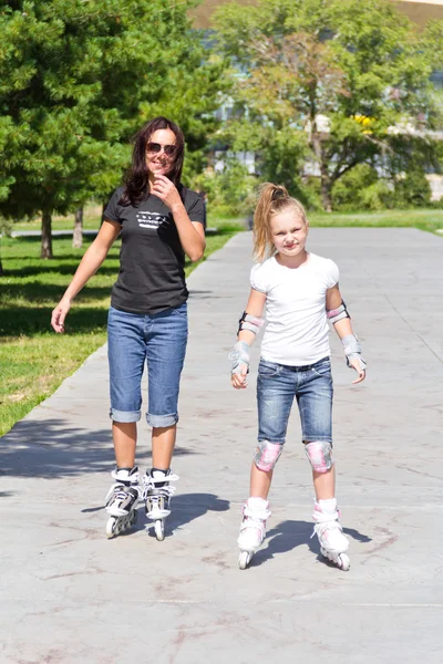 Mother and daughter on roller skates in summer — Stock Photo, Image