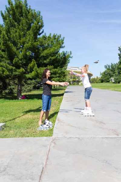 Mother and daughter on roller skates in summer — Stock Photo, Image