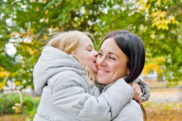 Mother and daughter kiss in autumn — Stock Photo, Image