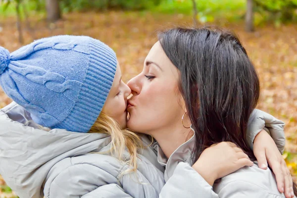 Mother and daughter kiss in autumn — Stock Photo, Image