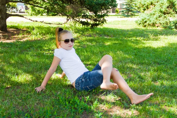 Menina sorridente em vidro de sol com joelho dolorido — Fotografia de Stock