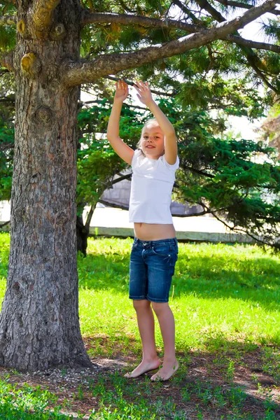 Fille en été essayer de sauter sur l'arbre — Photo