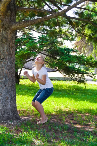 Chica en verano tratar de saltar en el árbol — Foto de Stock