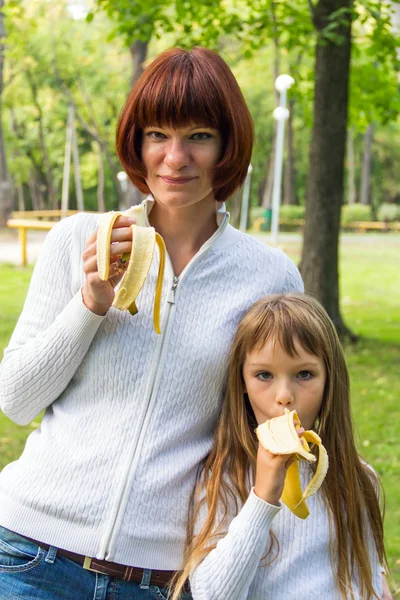 Mor och dotter äta banan — Stockfoto