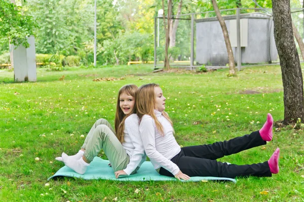 Two girls sitting on grass — Stock Photo, Image