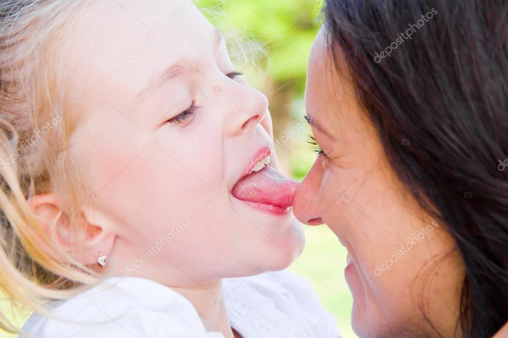 Photo of kissing mother and daughter in summer. 