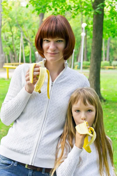Madre e hija comiendo plátano — Foto de Stock