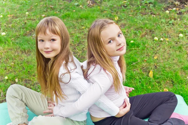 Twee meisjes zitten op gras — Stockfoto