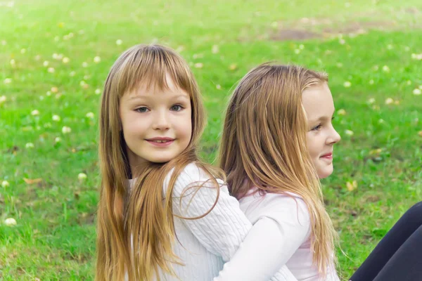 Two girls sitting on grass — Stock Photo, Image