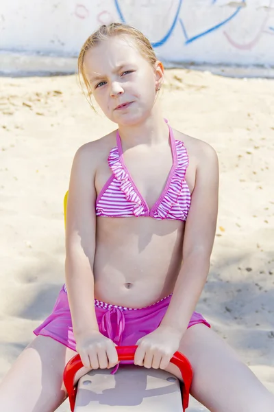 Cute girl at playground in pink swimsuit