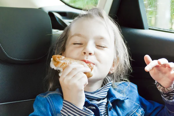 Manger fille mignonne assis à l'intérieur de la voiture — Photo