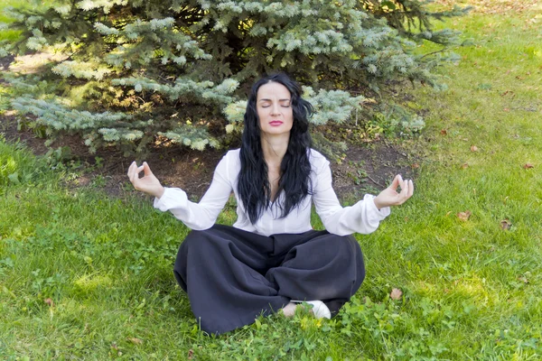 Morena sobre hierba verde en pose de yoga — Foto de Stock