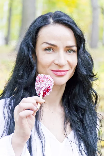 Morena comiendo caramelos rojos con pelos largos — Foto de Stock