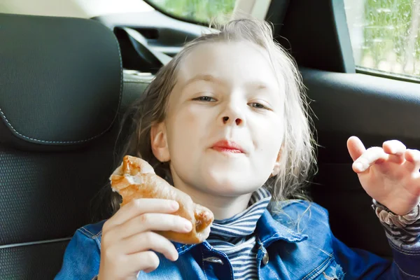 Eating cute girl sitting inside car — Stock Photo, Image