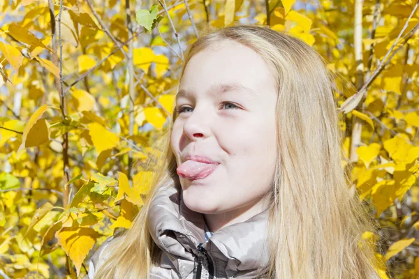 Cute girl in sunlight put out tongue — Stock Photo, Image