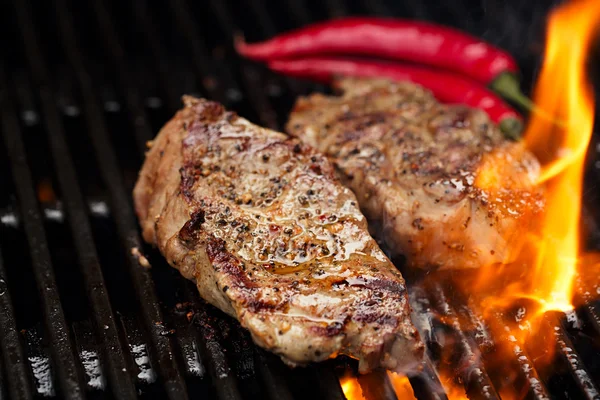 Bife de porco na churrasqueira com chama — Fotografia de Stock