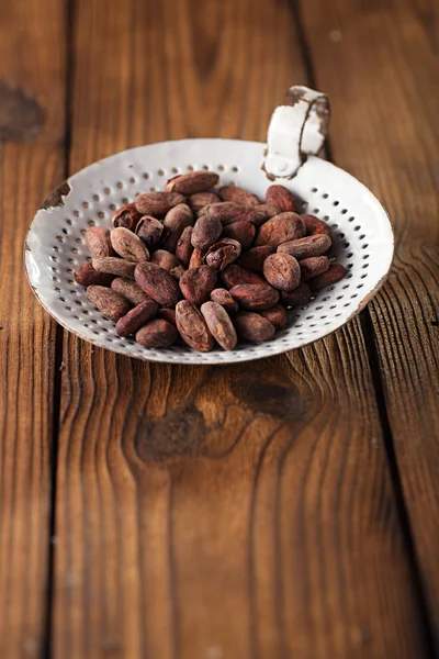 Roasted cocoa chocolate beans in old sieve — Stock Photo, Image